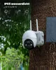 A white security camera with a solar panel attached to a tree trunk, with rain falling. Náhled obrázku produktu