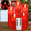 A set of red LED candles with a remote control on a wooden surface, with a blurred background of lights and greenery. Produktbild-Vorschau