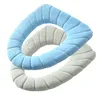 Two toilet seat covers, one light blue and one light gray, are arranged in a crisscross pattern against a white background. Produktbild-Vorschau