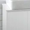 A close-up view of a white bathroom vanity with fluted cabinet doors, with a white sink on top. Produktbild-Vorschau