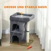 A dark gray cat tree with two cubbies and a scratching post, placed on a wooden floor next to a white curtain. A small orange toy is on the floor. Produktbild-Vorschau