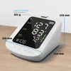 A white digital blood pressure monitor with a black screen displaying readings, placed on a wooden surface. Produktbild-Vorschau