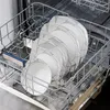 A close-up view of a dishwasher rack filled with clean dishes, including plates and bowls. Produktbild-Vorschau