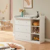 A white changing table with drawers and shelves is shown in a child's room, with toys and decor. Podgląd zdjęcia produktu