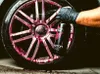 A gloved hand sprays a cleaning product onto a car wheel. Produktbild-Vorschau