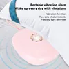 A pink portable vibration alarm clock is placed on a surface next to a white pillow. Podgląd zdjęcia produktu