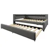 A gray upholstered daybed with a pull-out trundle bed extended. Voir les images du produit