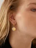 Close-up of a woman's ear wearing a gold earring with a moon pendant. Anteprima dell’immagine prodotto