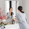 A woman is brushing her teeth in front of a lighted mirror in a bathroom. Produktbild-Vorschau