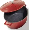 A red oval cast iron pot with a speckled black interior and a partially open lid. Voir les images du produit