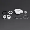 A collection of white plumbing parts, including a drain body, seals, and pipes, arranged on a dark gray background. Voir les images du produit