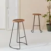 Two bar stools with wooden seats and black metal legs are shown in a room with a white door and a potted plant. Anteprima dell’immagine prodotto