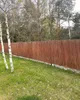 A woven reed fence is shown in a grassy yard with trees in the background. Produktbild-Vorschau