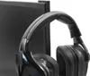 A black headset is hanging on a monitor hook attached to a computer monitor. Produktbild-Vorschau