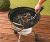 A hand is using a tool to arrange charcoal in a grill. Produktbild-Vorschau
