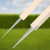 Two wooden posts with metal spikes attached, set against a blurred background of green grass and a blue sky. Produktbild-Vorschau
