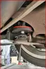 Close-up view of a car's suspension system, specifically a spring compressor tool being used. Produktbild-Vorschau
