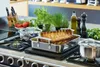 A rack of lamb is being roasted in a kitchen setting with fresh ingredients and cookware. Produktbild-Vorschau