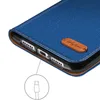 Close-up of a blue flip case for a smartphone, showing the charging port and a small brown leather tag with a logo. Anteprima dell’immagine prodotto