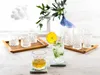 A set of crystal cut glasses, some empty and some filled with drinks, arranged on a wooden tray and coasters. Produktbild-Vorschau