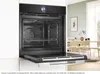 An open built-in oven is shown in a modern kitchen setting, with a dining area visible in the background. Produktbild-Vorschau