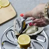 A hand is using a lemon squeezer to squeeze a lemon onto an oyster on a serving platter. Voir les images du produit