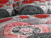 A close-up view of bedding with a circular, mandala-like pattern in gray, red, black, and white. Produktbild-Vorschau