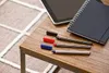A tablet, notebook, and several fineliner pens are arranged on a wooden table. Produktbild-Vorschau