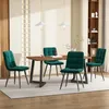 A dining room set with a wooden table and four green velvet chairs. Produktbild-Vorschau