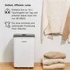 A white Bosch dehumidifier is shown next to stacked folded clothes and hanging sweaters, with descriptive text about its features. Produktbild-Vorschau