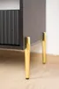 Close-up of the bottom part of a black cabinet with gold legs. Produktbild-Vorschau