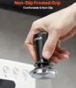 A hand holding a black espresso tamper over a coffee machine. Produktbild-Vorschau