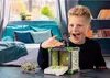 A boy is playing with a toy battle cave and creature in a bedroom. Produktbild-Vorschau