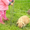 A child interacting with a rabbit in a pen outdoors. Produktbild-Vorschau