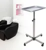 A salon trolley with a metal tray and a five-star base with wheels, set against a blurred background of salon chairs and sinks. Náhled obrázku produktu