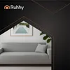 A modern living room scene featuring a gray sofa with a decorative pillow, set against a white wall with a framed picture of a swimming pool. The image is framed by dark, angled graphic elements with copper accents, and the brand logo 'Ruhhy' is visible in Podgląd zdjęcia produktu