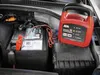 A car battery charger is connected to a car battery in an engine bay. Produktbild-Vorschau