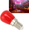 A close-up of a red LED light bulb with a silver base, with a blurred background image of a modern room with colorful lighting and seating. Podgląd zdjęcia produktu