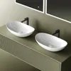 Two white oval vessel sinks with black faucets mounted on a green vanity. Produktbild-Vorschau