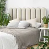 A close-up of a bed with a cream-colored headboard and a textured grey throw blanket. Anteprima dell’immagine prodotto