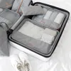 A set of packing cubes for luggage, neatly organized inside an open suitcase, with a pair of white sneakers placed in front. Voir les images du produit