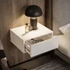 A white floating nightstand with an open drawer, a lamp, and perfume bottles on top. Produktbild-Vorschau