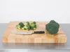 A wooden cutting board with broccoli florets and a whole head of broccoli, along with a knife. Anteprima dell’immagine prodotto