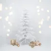 A white artificial Christmas tree with gifts and ornaments around its base, set against a white background with bokeh lights. Produktbild-Vorschau