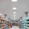 A view down an aisle in a brightly lit supermarket, with shelves stocked with various products on both sides. Produktbild-Vorschau