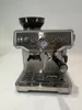 A silver espresso machine with a built-in grinder is shown against a white background. Produktbild-Vorschau