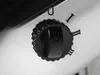 A close-up view of a black rotary dial on a white appliance, with Roman numerals indicating settings. Produktbild-Vorschau
