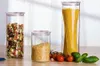 Three glass jars filled with pasta and grains, with tomatoes and basil in the foreground. Produktbild-Vorschau