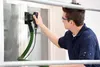 A man is using a sander on a window frame. Produktbild-Vorschau