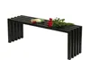 A black metal garden bench with a bouquet of red roses and a small book on top, set against a white background. Produktbild-Vorschau